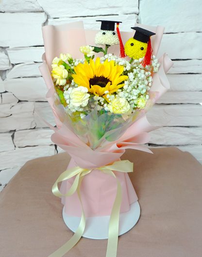 A084 ช่อดอกไม้แสดงความยินดีให้บัณฑิต จัดด้วยดอกปิงปองบัณฑิต ดอกทานตะวัน และคาร์เนชันสเปรย์ ห่อกระดาษสีชมพูอ่อน